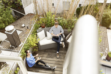 Junges Paar entspannt sich auf dem Balkon, sitzt auf der Couch und benutzt einen Laptop - PESF01165