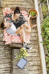 Junges Paar sitzt im Sommer auf dem Balkon und hält sich an den Händen - PESF01185