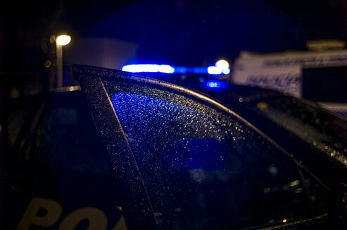 Spanien, Madrid, Regen, der nachts auf das Fenster eines Polizeiautos fällt - OCMF00253