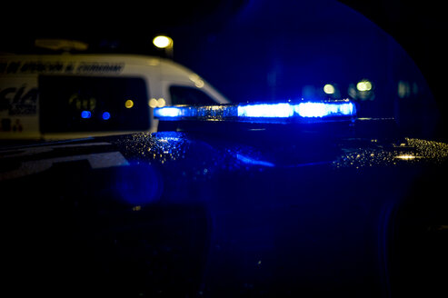 Spain, Madrid, rain falling on a police car at night - OCMF00255