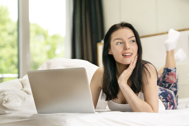Junge Frau im Bett liegend, mit Laptop am Morgen - PESF01205