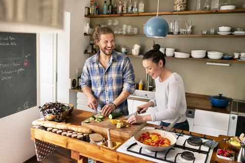 Junges Paar, das gemeinsam Essen zubereitet und Spaghetti probiert, lizenzfreies Stockfoto