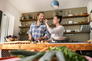 Young couple preparing food together, tasting spaghetti - PESF01225