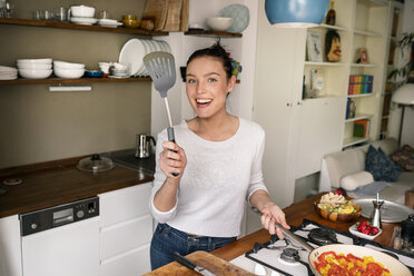 Young woman preparing food, pointing with spatula - PESF01228