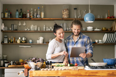 Young couple preparing spaghetti together, using online recipe - PESF01237