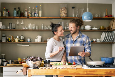 Young couple preparing spaghetti together, using online recipe - PESF01238