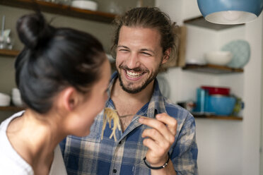 Young couple preparing food together, tasting spaghetti - PESF01242