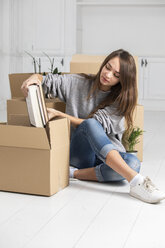 Woman sitting on the floor packing cardboard boxes - ERRF00732