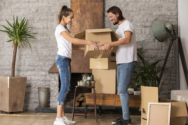 Smiling couple holding cardboard box in new home - ERRF00738