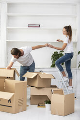 Couple unpacking cardboard boxes and furnishing new home - ERRF00743