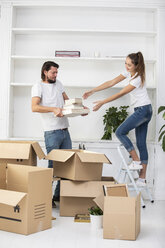 Couple unpacking cardboard boxes and furnishing new home - ERRF00744