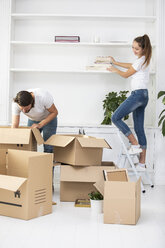 Couple unpacking cardboard boxes and furnishing new home - ERRF00745