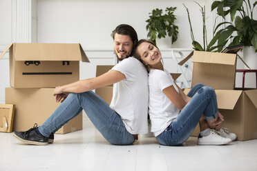Glückliches Paar mit Kartonschachteln auf dem Boden in der neuen Wohnung - ERRF00755