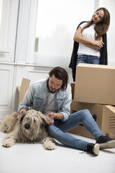 Ehepaar mit Hund und Kartons im neuen Zuhause - ERRF00761