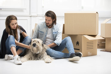 Ehepaar mit Hund und Kartons auf dem Boden in der neuen Wohnung - ERRF00762