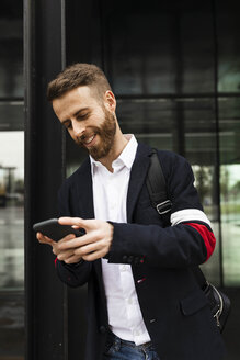 Smiling stylish businessman using cell phone in the city - JRFF02579