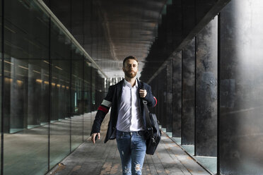 Stylish businessman walking in colonnade in the city - JRFF02581