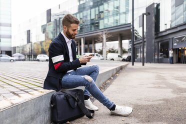 Stilvoller Geschäftsmann, der in der Stadt sitzt und ein Mobiltelefon benutzt - JRFF02586