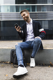 Stilvoller Geschäftsmann, der in der Stadt sitzt und ein Mobiltelefon benutzt - JRFF02587