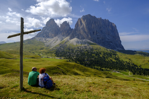 Italien, Südtirol, Sellagruppe, Wanderer sitzt am Gipfelkreuz, lizenzfreies Stockfoto