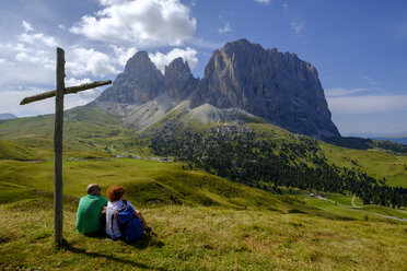 Italien, Südtirol, Sellagruppe, Wanderer sitzt am Gipfelkreuz - LBF02356
