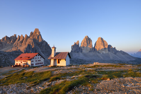 Kapelle und Refugio Antonio Locatelli mit den berühmten Drei Zinnen und dem Berg Paterno bei Sonnenaufgang, Trentino-Südtirol, Italien, lizenzfreies Stockfoto