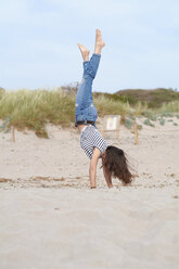 Spanien, Menorca, barfuß, junge Frau macht Handstand am Strand - IGGF00761