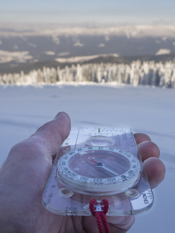 Germany, Upper Bavarian Forest Nature Park, man's hand holding compass in winter stock photo