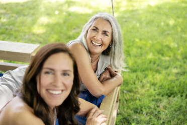 Porträt von zwei glücklichen Frauen, die sich auf einem Hängebett im Garten entspannen - PESF01264