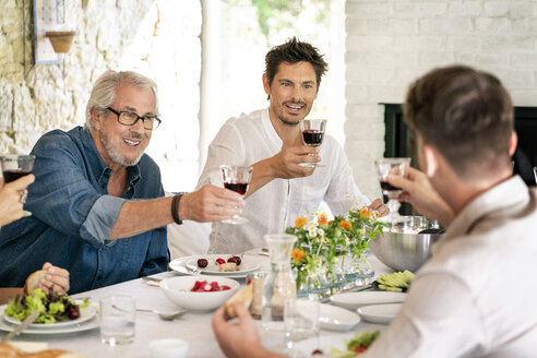 Glückliche Familie beim gemeinsamen Essen und Anstoßen mit Weingläsern - PESF01280