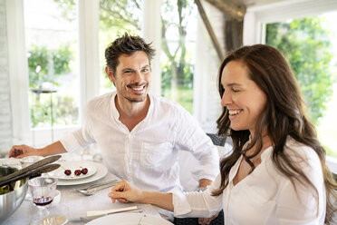 Happy couple sitting at dining table - PESF01283