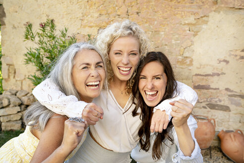 Porträt von drei aufgeregten Frauen unterschiedlichen Alters, die sich umarmen und jubeln - PESF01322