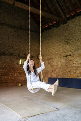 Happy woman on a swing in a hall - PESF01324