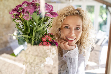 Porträt einer lächelnden jungen Frau mit Blumen - PESF01335