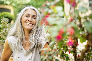 Portrait of smiling woman with long grey hair in garden - PESF01352