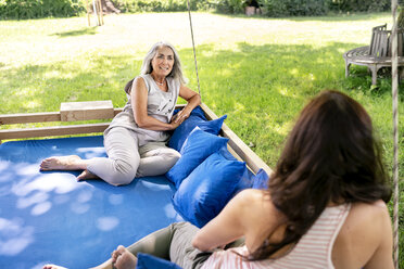 Zwei Frauen entspannen sich auf einem Hängebett im Garten - PESF01371