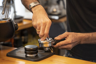Nahaufnahme eines Barista, der den Filter einer Kaffeemaschine in einem Coffeeshop vorbereitet - OCMF00266
