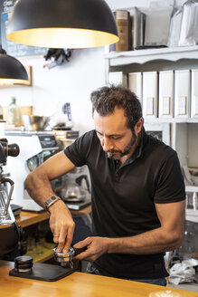 Barista bei der Vorbereitung des Siebträgers einer Kaffeemaschine in einem Kaffeegeschäft - OCMF00267