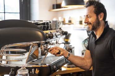 Lächelnde Barista bei der Kaffeezubereitung in einem Café - OCMF00268