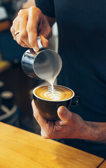 Nahaufnahme eines Barista bei der Zubereitung von Cappuccino in einem Café - OCMF00277