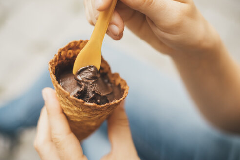 Woman's hand holding ice cream cone with cholocolate ice, close-up - JSCF00136