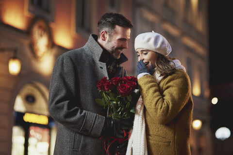 Mann schenkt seiner Freundin einen Strauß roter Rosen zum Valentinstag, lizenzfreies Stockfoto