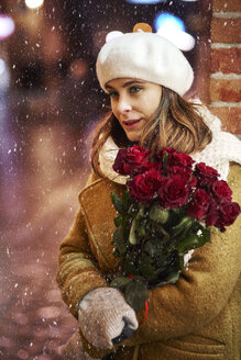 Porträt einer jungen Frau mit einem Strauß roter Rosen im Winter - ABIF01167