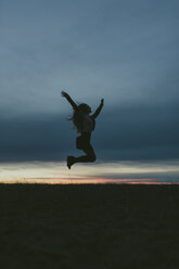 Silhouette of happy woman in nature jumping in the air at sunset - JPF00350