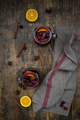 Glasses of mulled wine with cranberries, cinnamon sticks, orange and star anise on dark wood - LVF07757