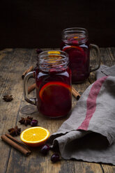 Glasses of mulled wine with cranberries, cinnamon sticks, orange and star anise on dark wood - LVF07758