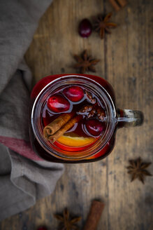 Glas Glühwein mit Preiselbeeren, Zimtstangen, Orange und Sternanis auf dunklem Holz, Fokus auf Vordergrund - LVF07759