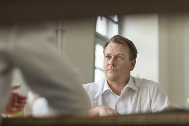 Konzentrierter Geschäftsmann, der einen Kollegen im Büro ansieht - PAF01851