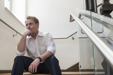 Thoughtful businessman sitting in staircase - PAF01873