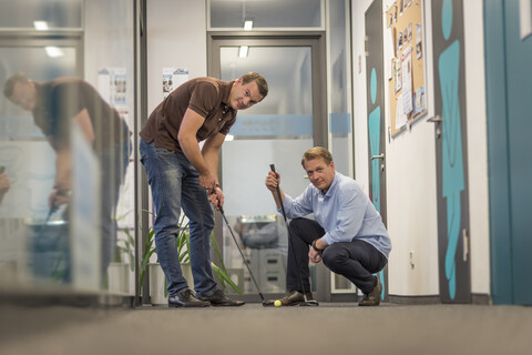 Zwei Geschäftsleute spielen Golf im Büro, lizenzfreies Stockfoto